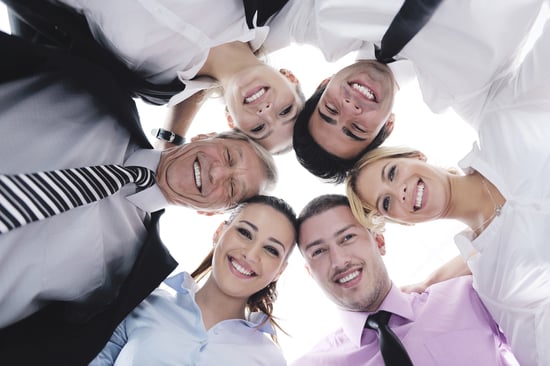 Closeup of happy business people with their heads together representing concept of ftiendship and teamwork isolated on white background