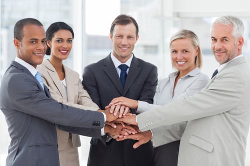 Group of smiling business people piling up their hands together in the workplace