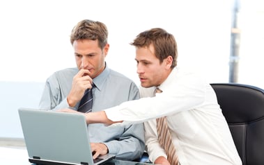 Two handsome businessmen working together on a project sitting at a table in the office